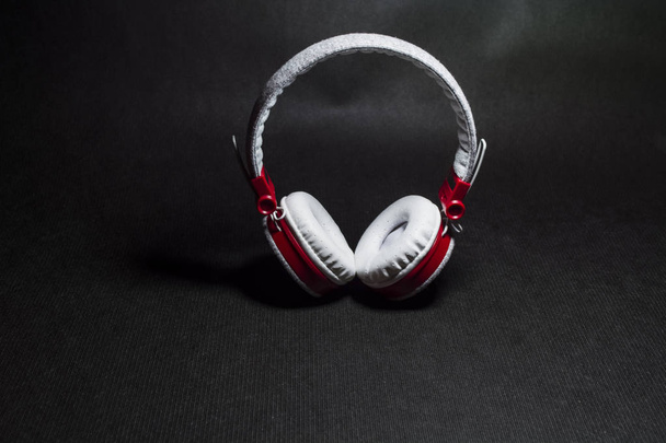 Grote draagbare en multi-gekleurde oortelefoons voor het beluisteren van muziek. Witte en rode kleur. Op een monofone zwarte achtergrond.  - Foto, afbeelding