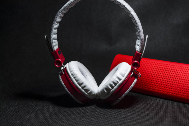 Nagy hordozható és sokszínű fülhallgató és piros hangszóró, zenét hallgatni. Fehér és vörös színű. Fekete háttér - Fotó, kép