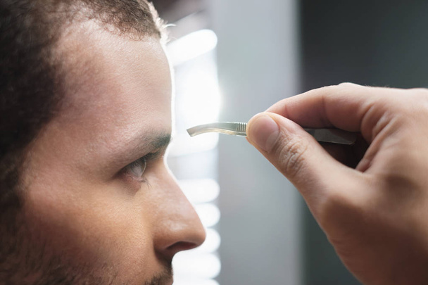 Closeup mužská tvář člověka škubání vlasů obočí pro krásu - Fotografie, Obrázek