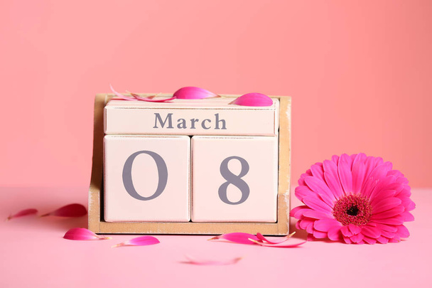 Wooden block calendar with flower on table against color background. International Women's Day - Photo, image