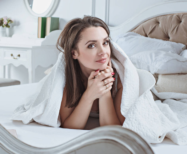 Portrait of a smiling lady relaxing on a luxurious bed - Fotografie, Obrázek