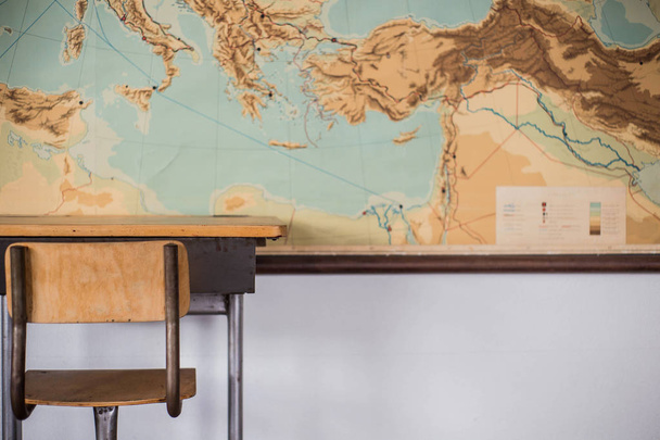 Empty desks at school classroom with world map. - Фото, изображение
