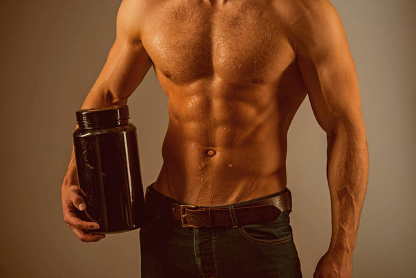 Stimulating muscle growth with anabolic steroids. Anabolic hormone increases muscle strength. Vitamin nutrition. Healthy diet. Strong man hold vitamin bottles. Man with six pack abs. Keeping a diet - Foto, Bild