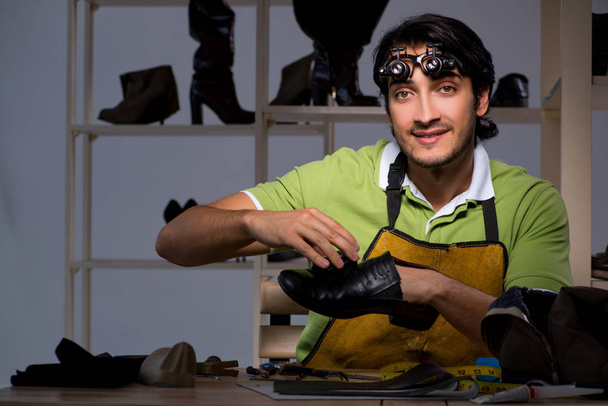 Jonge schoenmaker in workshop bij nacht  - Foto, afbeelding