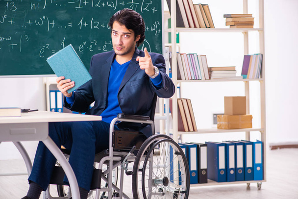 Young handsome man in wheelchair in front of chalkboard  - Fotografie, Obrázek