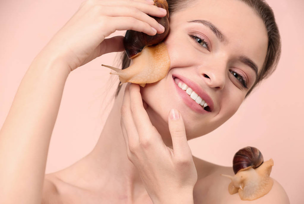 Young woman with giant Achatina snails on color background - Photo, Image