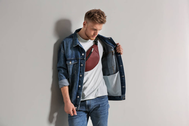 Fashionable young man with bag on light background - Fotó, kép