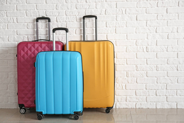 Packed suitcases near white brick wall - 写真・画像
