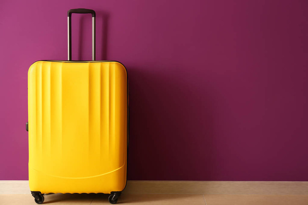 Упакованный чемодан рядом с цветной стеной
 - Фото, изображение
