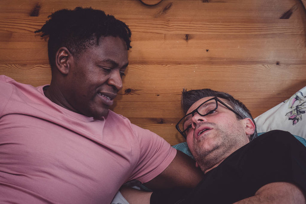 Un couple gay interracial parle, couché dans leur chambre
.  - Photo, image