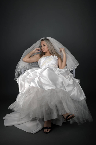 Beautiful blonde bride in a white dress on a black background - Valokuva, kuva