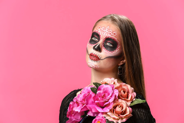 Молодая женщина с раскрашенным черепом на лице на День мертвых в Мексике на цветном фоне - Фото, изображение