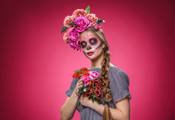 Junge Frau mit aufgemaltem Totenkopf zum mexikanischen Tag der Toten vor farbigem Hintergrund - Foto, Bild