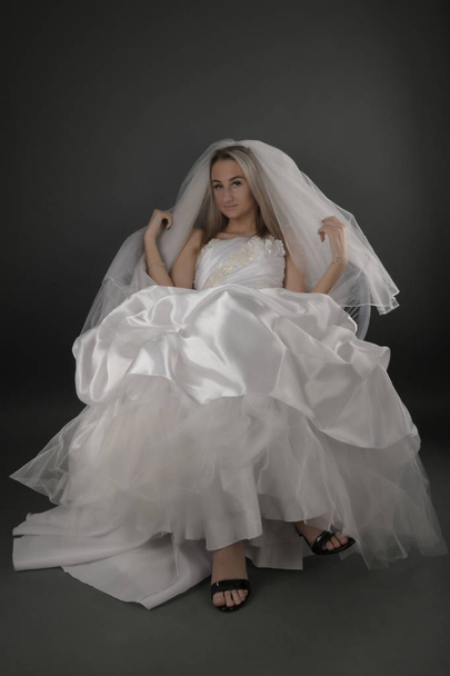 Beautiful blonde bride in a white dress on a black background - Фото, зображення