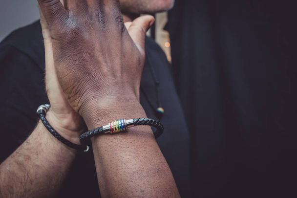 Ένα διαφυλετικό ζευγάρι ομοφυλόφιλων ποζάρουν στην jest με στηρίγματα - μπροστά σε ένα μαύρο φόντο σε ένα στούντιο φωτογραφίας.  - Φωτογραφία, εικόνα