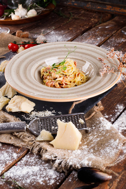Tészta Carbonara parmezán sajttal és szósszal egy tányéron, fa alapon - Fotó, kép