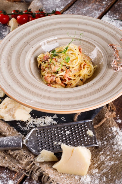 Pasta Carbonara with Parmesan cheese and sauce on a plate on a wooden background - Fotoğraf, Görsel