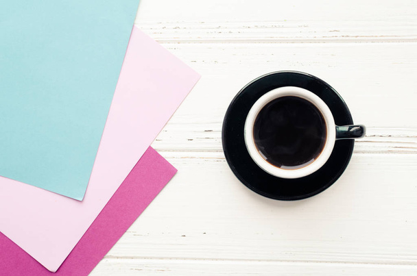Tasse schwarzen Kaffee und rosa, blauen und magenta Papier Textur auf weißem Holztisch. Kaffeepause bei der Wahl der Farbe stilvolles Schema im Wohnbereich. harmonische und schöne Kombination. Ansicht von oben. - Foto, Bild