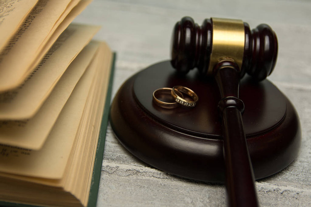 Law and Justice. Judge gavel and wedding rings on concrete background - 写真・画像