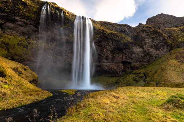 Photo of the Magnificent Seljalandsfoss Waterfall Falling Down a Mountainside in Iceland on a Sunny Fall Day - Fotoğraf, Görsel