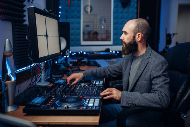 Sound engineer working at the remote control panel in the recording studio. Musician at the mixer, professional audio processing - Foto, immagini