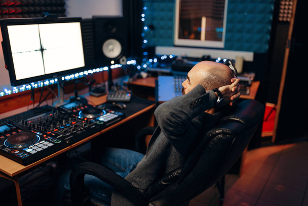 Mężczyzna inżyniera dźwięku w panelu zdalnego sterowania, widok z tyłu, studio nagrań. Muzyk na mikser, profesjonalnego przetwarzania audio - Zdjęcie, obraz