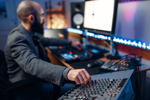 Sound operator at remote control panel in audio recording studio. Musician at the mixer, professional music mixing - Photo, Image