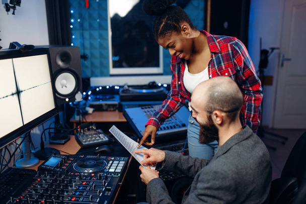 Operator dźwięku i wokalistka o panel zdalnego sterowania w studio nagrań audio. Muzyk na mikser, miksowania muzyki profesjonalne - Zdjęcie, obraz