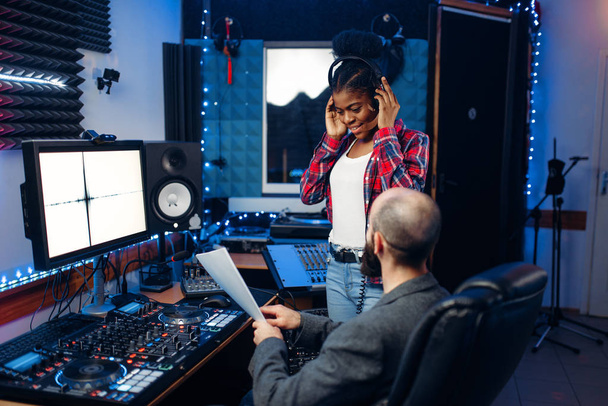 Zvukař a zpěvačku na dálkový ovládací panel v audio nahrávací studio. Hudebník v mixéru, profesionální hudební míchání - Fotografie, Obrázek
