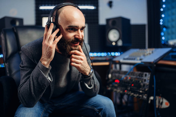 Sound producer in headphones listens composition of female singer in recording studio. Professional audio and music mixing technology - Foto, imagen