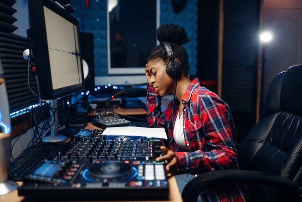 Vrouwelijke geluid operator werkt op het paneel van de afstandsbediening in de audio-opnamestudio. Muzikant in de mixer, professionele muziek mixen - Foto, afbeelding