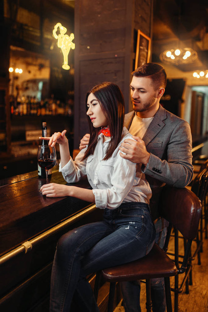 Man and woman relax, couple at wooden bar counter. Lovers leisures in pub, husband and wife relaxing together in nightclub - Photo, Image