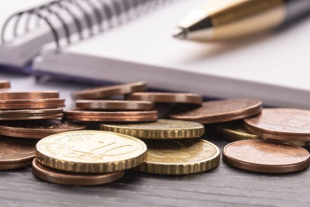 古い黒の木製のテーブルにユーロのユーロ硬貨のスタック。ペン、ノート。住宅関連支出を計画、支払い、会計の概念 - 写真・画像
