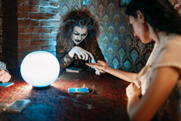 Kadın foreteller el ile bir kristal top, büyücülük tahmin. Korkunç cadı bir büyü, manevi ruh çağırma seansı genç kadın okur - Fotoğraf, Görsel