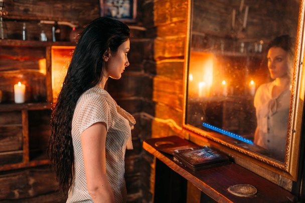 Jonge vrouw in de spiegel op spirituele Seance, hekserij. Vrouwelijke foreteller roept de geesten, magie - Foto, afbeelding