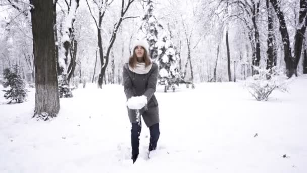 Bellezza invernale. Una bella giovane donna getta neve nel parco cittadino. Rallentatore
 - Filmati, video