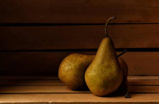 Three fresh picked Bosc Pears in a wooden packing crate, horizontal format with copy space. - Foto, Bild