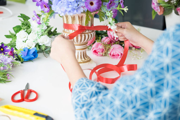 jonge vrouwen business eigenaar bloemist maken of schikken van kunstmatige bloemen vest in haar winkel, ambacht en hand maakte concept. - Foto, afbeelding