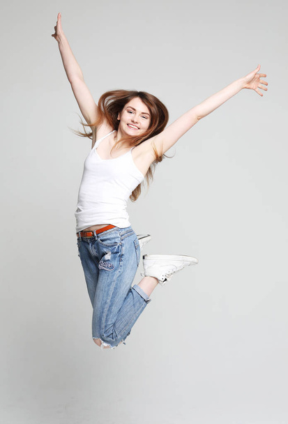 smiling young woman jumping in air over white  background  - Zdjęcie, obraz