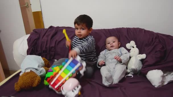 dois anos de idade e 4 meses de idade meninos brincando na cama roxa com xilofone e brinquedos macios
 - Filmagem, Vídeo