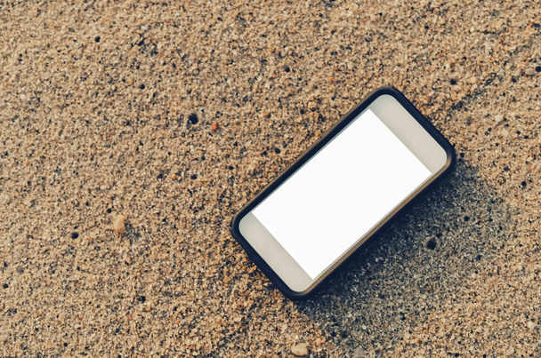Smart phone on sand beach texture background. White copy space of technology and travel nature concept. Vintage tone filter effect color style. - Photo, Image