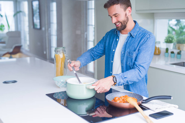 Handsome man cooking pasta at home - Фото, изображение