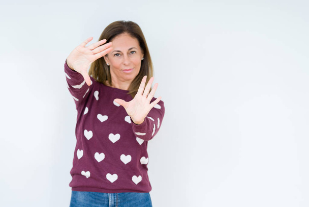 Красивая женщина средних лет носит сердечный свитер на изолированном фоне улыбается делая рамку с помощью ладоней рук и пальцев, камеры перспективы
 - Фото, изображение