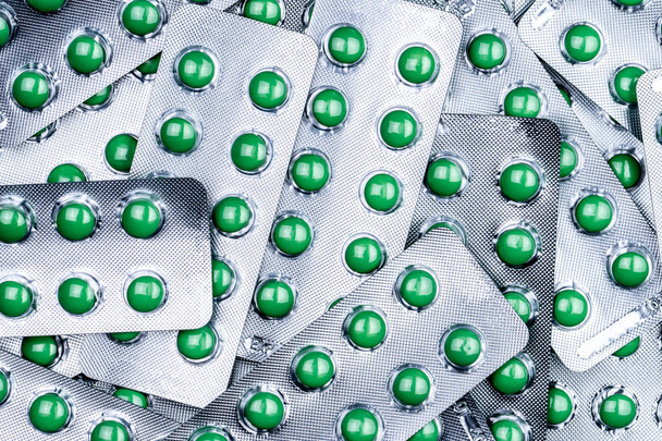 Крупный план груды круглых зеленых таблетки с сахарным покрытием в блистерной упаковке. Комбинируйте таблетки от кашля. Фармацевтический продукт. Фармацевтическая промышленность. Фармацевтическое образование. Лекарство от сухого кашля
. - Фото, изображение