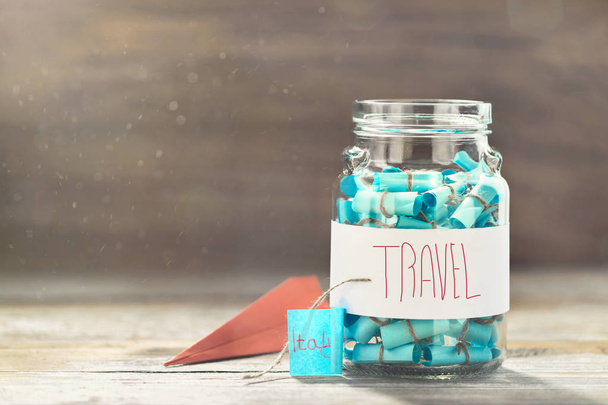 Glass jar with list of countries to visit and paper airplane. Creative travel background. Vacation planning - Foto, imagen