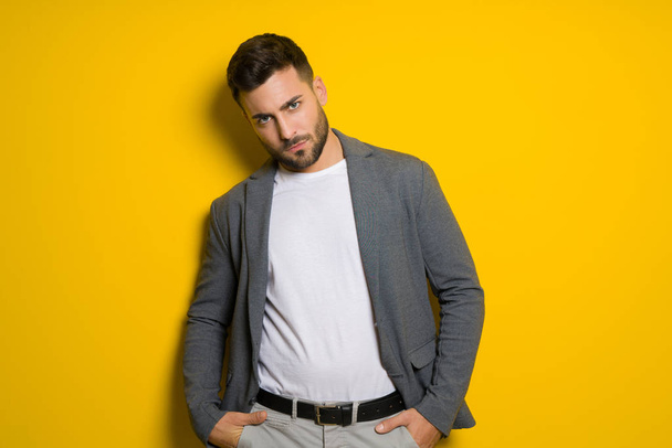 Young handsome man possing and modeling over yellow isolated background - Fotó, kép
