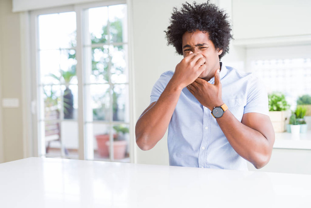 African American business man smelling something stinky and disgusting, intolerable smell, holding breath with fingers on nose. Bad smells concept. - Fotoğraf, Görsel