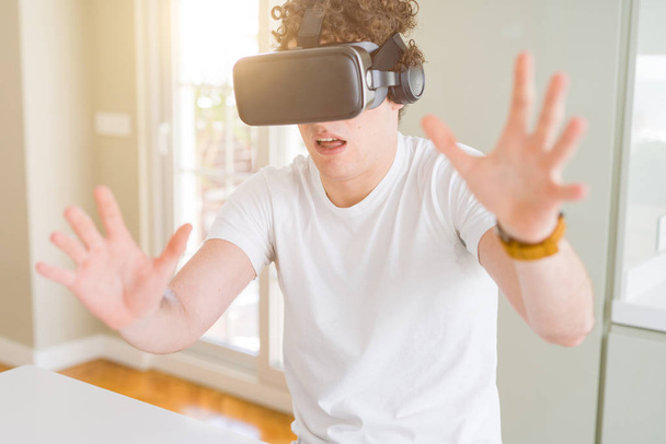 Jeune homme s'amusant à porter des lunettes de réalité virtuelle à la maison
 - Photo, image