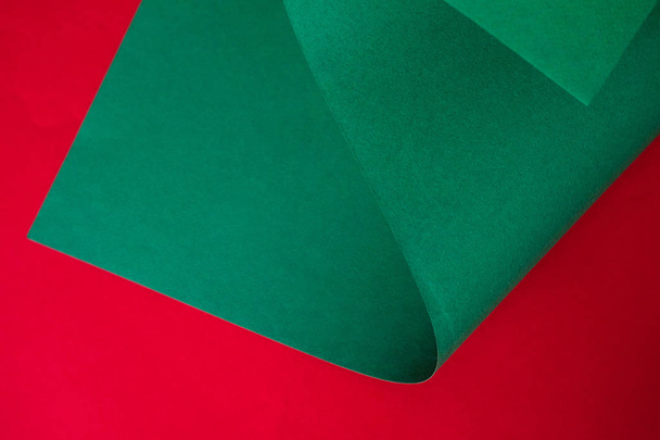 Jasny zielony arkusz papieru na czerwonym tle. Projekt papieru kolor monochromatyczny.    - Zdjęcie, obraz