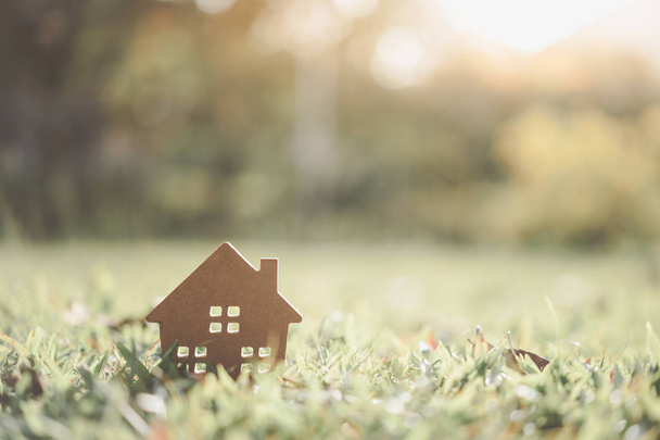 Kopieer ruimte van huis en leven concept. Klein model huis op groene gras met zonlicht abstracte achtergrond. Vintage Toon filter effect kleurstijl. - Foto, afbeelding